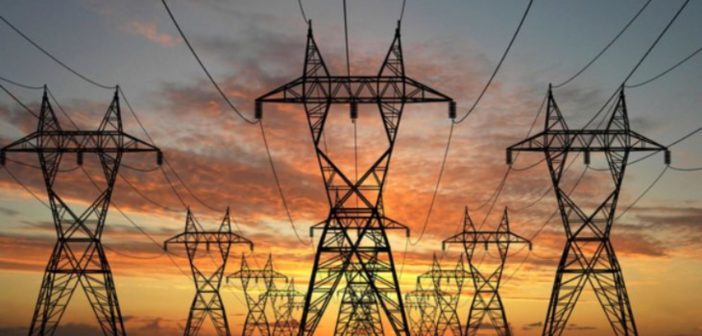 Electricity pylons stand against a sunset sky, symbolizing the challenge of how to decrease electricity load in the energy sector.